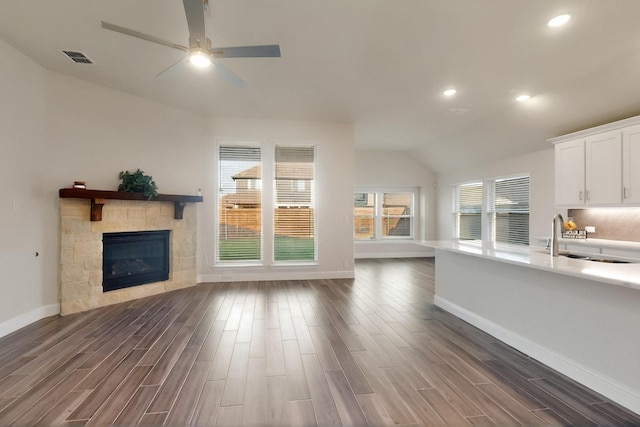 unfurnished living room featuring a sink, lofted ceiling, dark wood-style flooring, baseboards, and ceiling fan