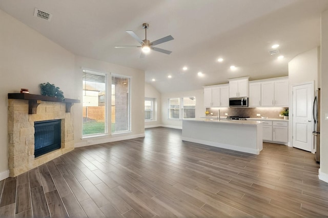 kitchen featuring stainless steel appliances, open floor plan, lofted ceiling, ceiling fan, and white cabinets