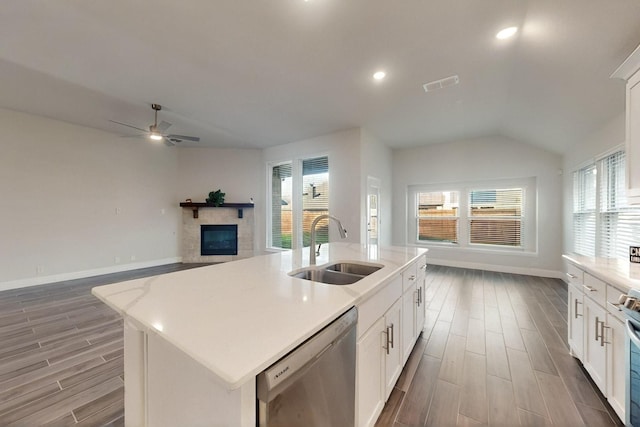 kitchen with dishwasher, a sink, wood tiled floors, a ceiling fan, and an island with sink