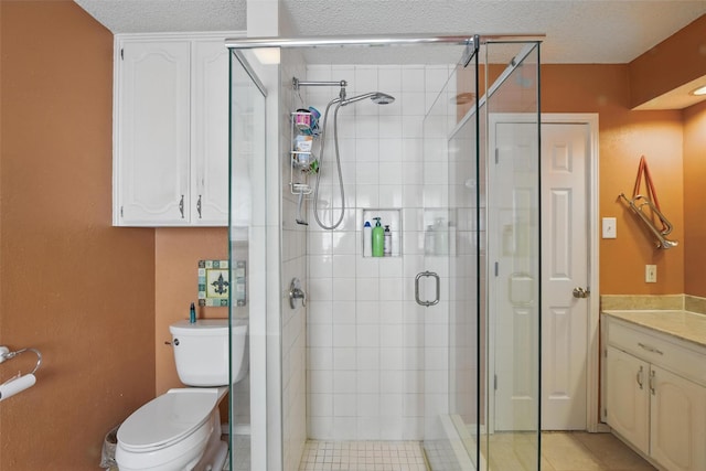 2606 N Carroll Ave, Southlake, TX 76092 - full bathroom with a stall shower, a textured ceiling, toilet, vanity, and tile patterned floors