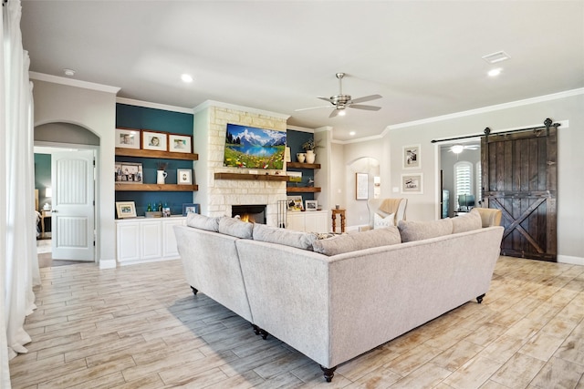 1456 Silent Springs Dr, Fort Worth, TX 76052 - living room featuring a barn door, a ceiling fan, crown molding, a stone fireplace, and light wood-type flooring