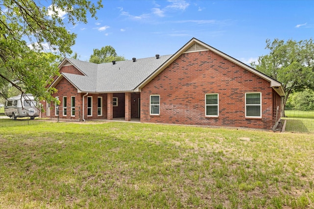 rear view of property featuring brick siding, a yard, and roof with shingles