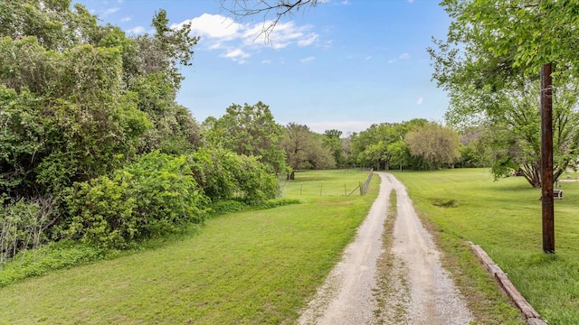 view of dirt / gravel road with a wooded view