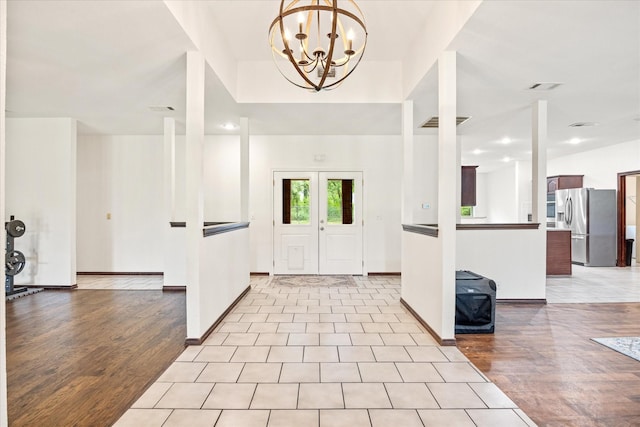entrance foyer with light wood-style floors, a chandelier, and baseboards