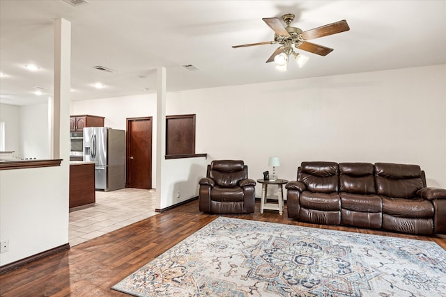 living area featuring a ceiling fan, wood finished floors, and baseboards