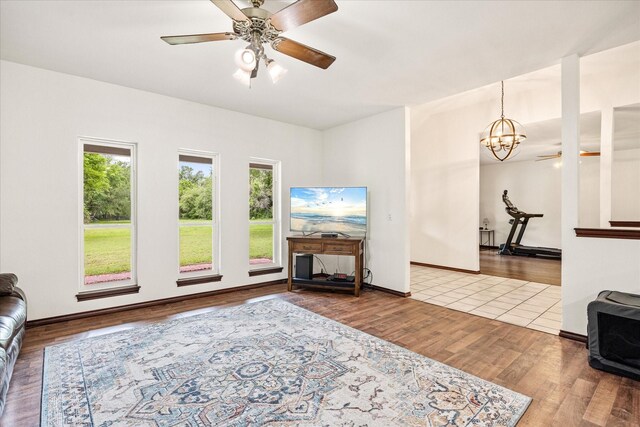 living area featuring a chandelier, wood finished floors, a ceiling fan, and baseboards