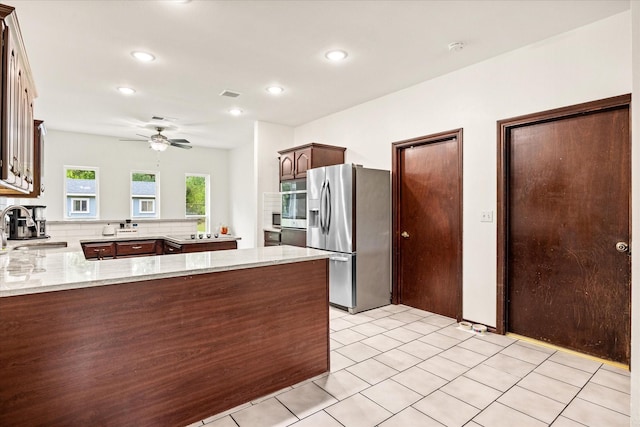 kitchen with appliances with stainless steel finishes, a sink, a peninsula, light stone counters, and recessed lighting
