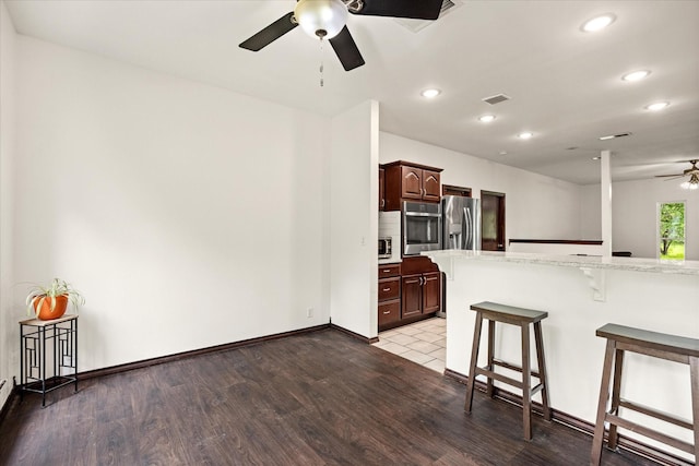kitchen featuring a ceiling fan, appliances with stainless steel finishes, a breakfast bar area, recessed lighting, and light wood-style flooring