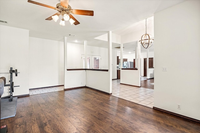 unfurnished living room with wood finished floors, a chandelier, a ceiling fan, and baseboards