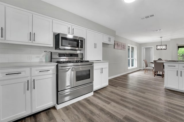 kitchen with stainless steel appliances, dark wood-type flooring, tasteful backsplash, white cabinetry, and light countertops