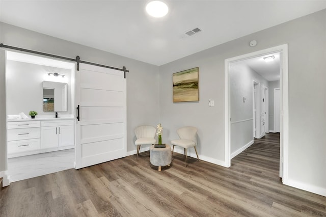 living area featuring a barn door, light wood-type flooring, and baseboards