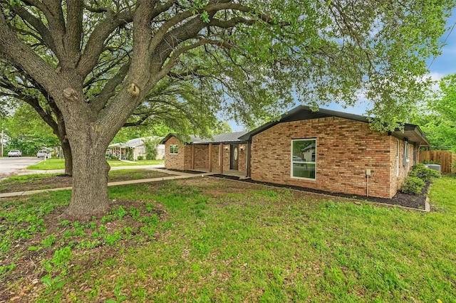 view of property exterior with brick siding and a lawn