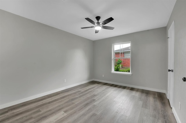 unfurnished room with wood finished floors, a ceiling fan, and baseboards