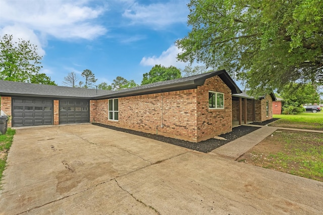 view of side of property with a garage, brick siding, and driveway