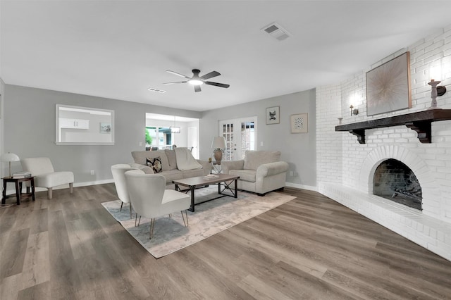 living area with a ceiling fan, wood finished floors, a fireplace, and baseboards