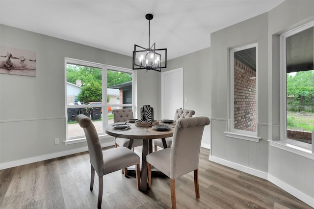 dining area featuring a chandelier, wood finished floors, plenty of natural light, baseboards, and a wainscoted wall