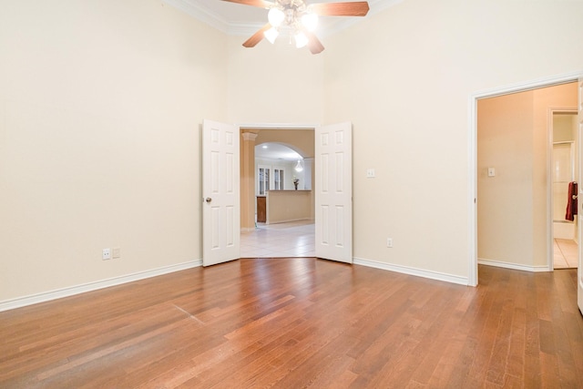 842 Turquoise Pt, Rockwall, TX 75032 - empty room with arched walkways, ceiling fan, a high ceiling, crown molding, and light wood-style flooring