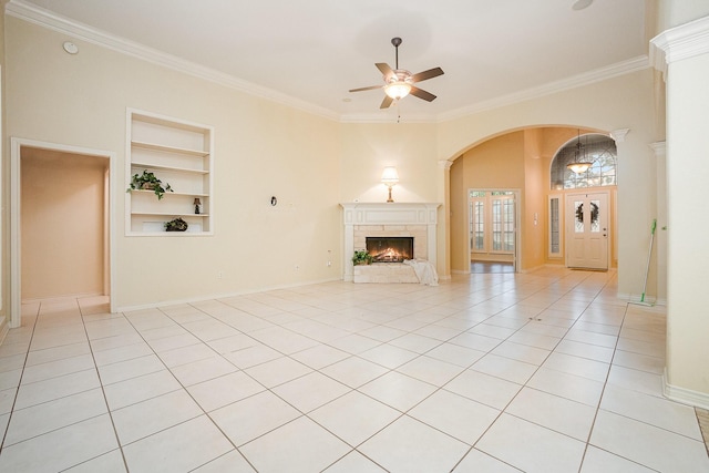 842 Turquoise Pt, Rockwall, TX 75032 - unfurnished living room featuring built in features, a ceiling fan, a warm lit fireplace, arched walkways, and crown molding