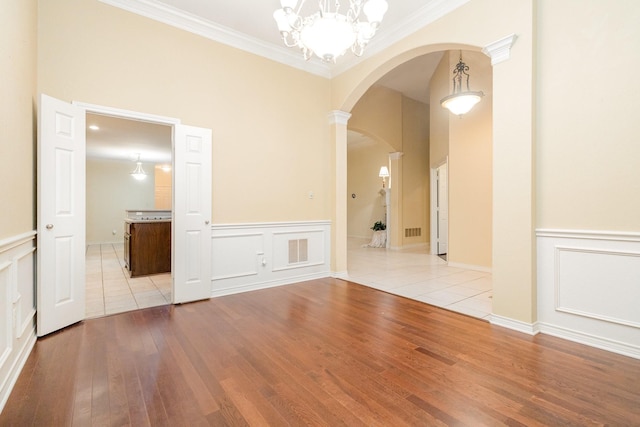 842 Turquoise Pt, Rockwall, TX 75032 - empty room with arched walkways, wood finished floors, ornamental molding, a decorative wall, and a wainscoted wall