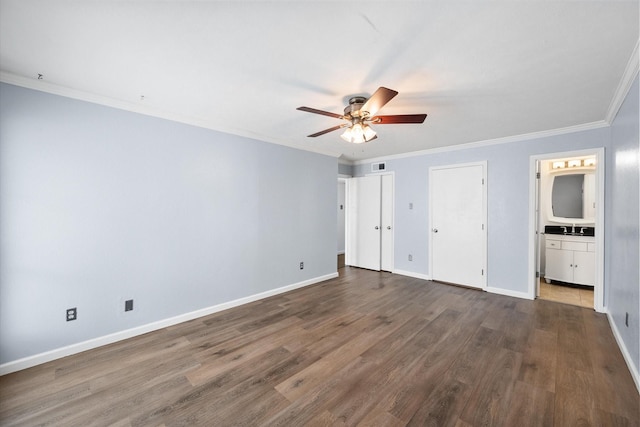 unfurnished bedroom with dark wood-type flooring, baseboards, crown molding, ensuite bath, and a sink