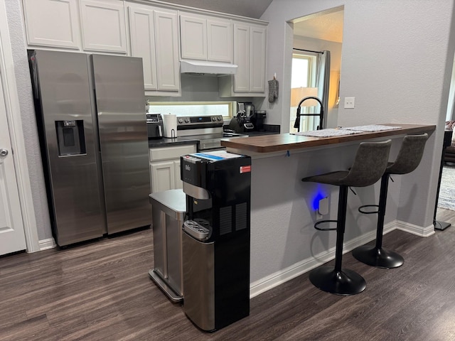 1253 E Ramsey Ave, Fort Worth, TX 76104 - kitchen with appliances with stainless steel finishes, under cabinet range hood, dark wood-style flooring, butcher block countertops, and a breakfast bar