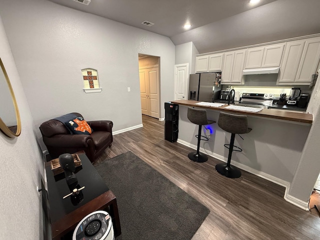 1253 E Ramsey Ave, Fort Worth, TX 76104 - kitchen featuring stainless steel appliances, vaulted ceiling, dark wood finished floors, a breakfast bar, and a peninsula