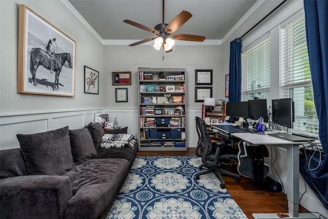 office space featuring a ceiling fan, wood finished floors, ornamental molding, and wainscoting