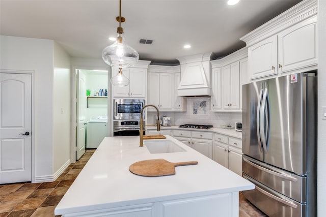 7333 Valencia Grove Ct, Fort Worth, TX 76132 - kitchen with stainless steel appliances, washer / dryer, custom range hood, a sink, and tasteful backsplash