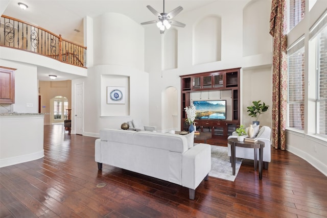 509 Wentworth Ln, Murphy, TX 75094 - living room with dark wood finished floors, a towering ceiling, arched walkways, a ceiling fan, and baseboards