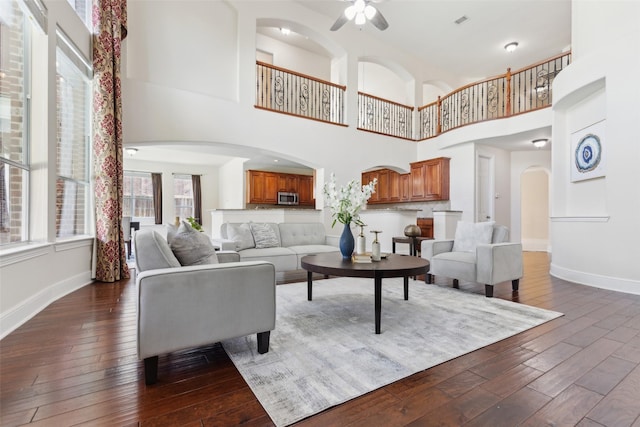 509 Wentworth Ln, Murphy, TX 75094 - living room featuring arched walkways, dark wood-type flooring, baseboards, and a high ceiling