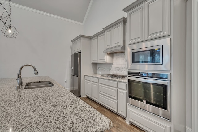 175 Calla Dr, Flower Mound, TX 75028 - kitchen with stainless steel appliances, a sink, ornamental molding, under cabinet range hood, and light stone counters