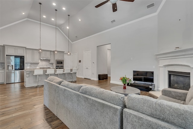 175 Calla Dr, Flower Mound, TX 75028 - living room featuring high vaulted ceiling, ceiling fan, a glass covered fireplace, light wood-type flooring, and baseboards