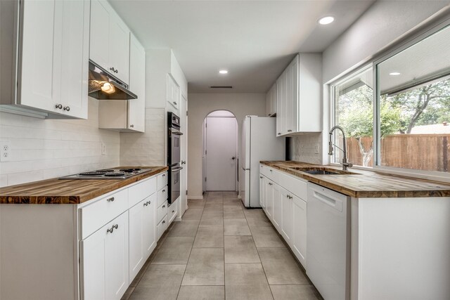 3301 Regent Dr, Plano, TX 75075 - kitchen with butcher block countertops, white appliances, a sink, under cabinet range hood, and backsplash