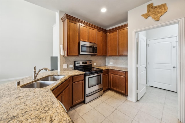 6552 Federal Hall St, Plano, TX 75023 - kitchen with stainless steel appliances, a sink, brown cabinetry, light stone countertops, and backsplash