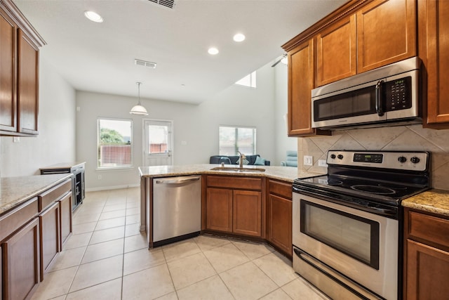 6552 Federal Hall St, Plano, TX 75023 - kitchen featuring stainless steel appliances, a sink, tasteful backsplash, a peninsula, and brown cabinets