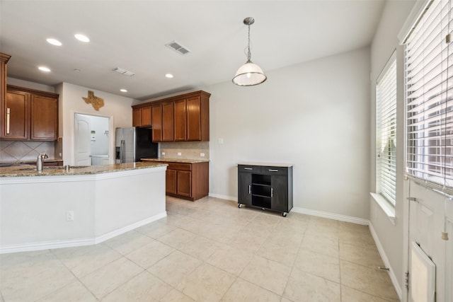 6552 Federal Hall St, Plano, TX 75023 - kitchen with stainless steel fridge, decorative backsplash, healthy amount of natural light, light stone countertops, and recessed lighting