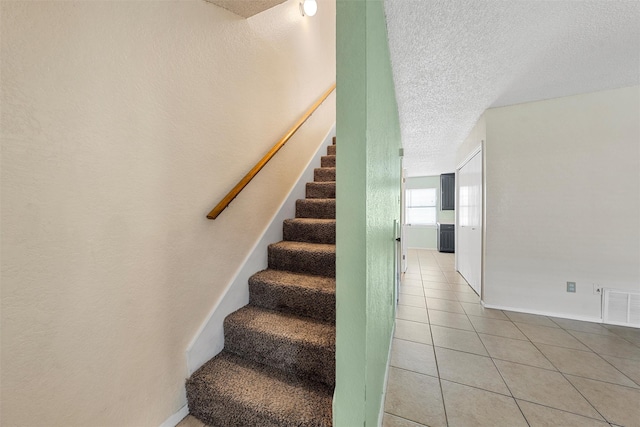 1226 Baylor Ave Unit 116, Waco, TX 76706 - stairway featuring a textured ceiling, tile patterned floors, and baseboards