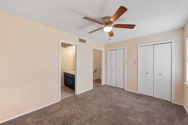 1226 Baylor Ave Unit 116, Waco, TX 76706 - unfurnished bedroom featuring multiple closets, light carpet, connected bathroom, a textured ceiling, and baseboards