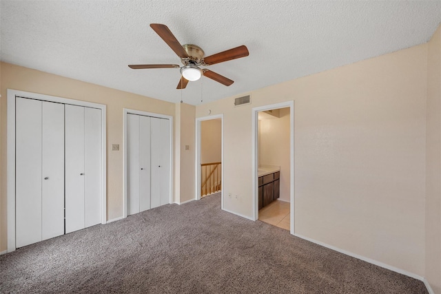 1226 Baylor Ave Unit 116, Waco, TX 76706 - unfurnished bedroom with multiple closets, light carpet, ensuite bath, a textured ceiling, and baseboards
