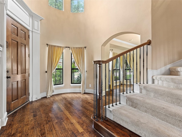 1413 Prairie Dr, Carrollton, TX 75007 - foyer entrance with stairs, a high ceiling, arched walkways, wood finished floors, and baseboards