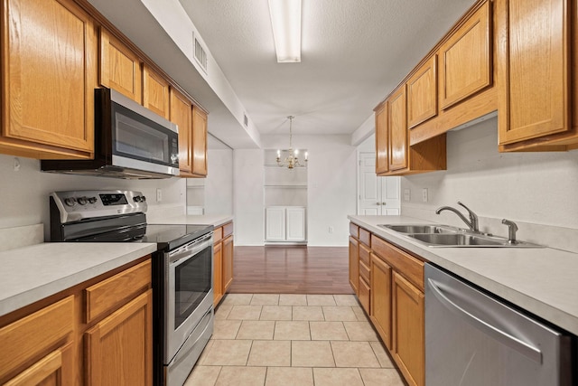 1120 Forest Creek St, Benbrook, TX 76126 - kitchen with stainless steel appliances, light countertops, a sink, and a chandelier