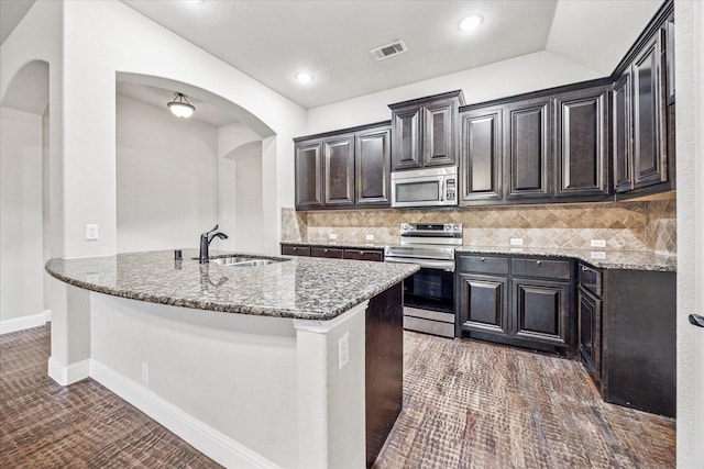 5013 Spruce, Krum, TX 76249 - kitchen featuring stainless steel appliances, light stone counters, arched walkways, a sink, and vaulted ceiling