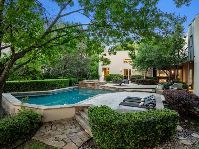 swimming pool with a patio and an in-ground hot tub