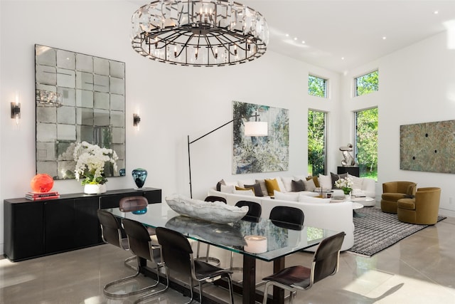 dining room featuring a high ceiling, concrete flooring, and a chandelier