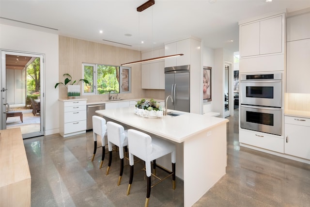 kitchen with stainless steel appliances, modern cabinets, a sink, a breakfast bar area, and light countertops
