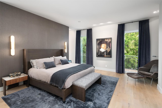 bedroom with light wood-style floors, baseboards, multiple windows, recessed lighting, and an accent wall