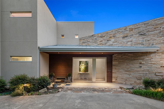 view of exterior entry with stone siding, a standing seam roof, and metal roof