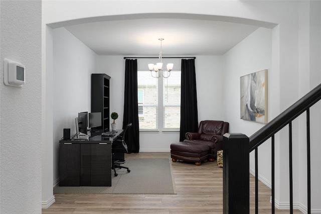 office area with arched walkways, wood finished floors, a chandelier, and baseboards