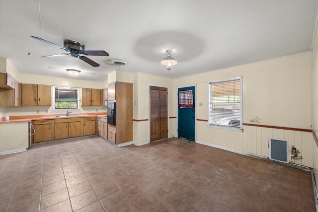 kitchen featuring a sink, light countertops, ceiling fan, and brown cabinets
