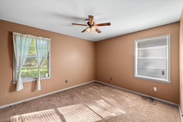 carpeted spare room with ceiling fan and baseboards